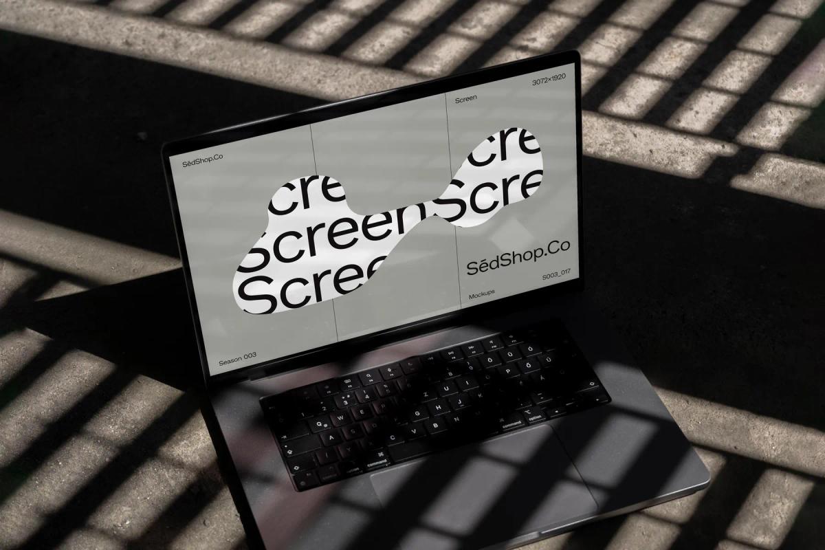 MacBook Pro screen mockup displaying a creative text design under the striped shadows of a grid.