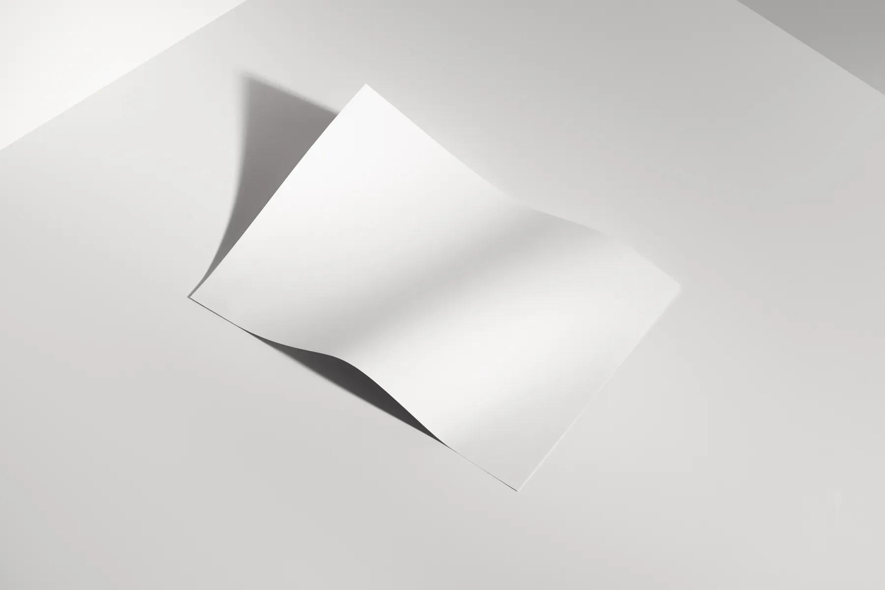 Curved blank A-size paper mockup, in a bright, shadowed environment.