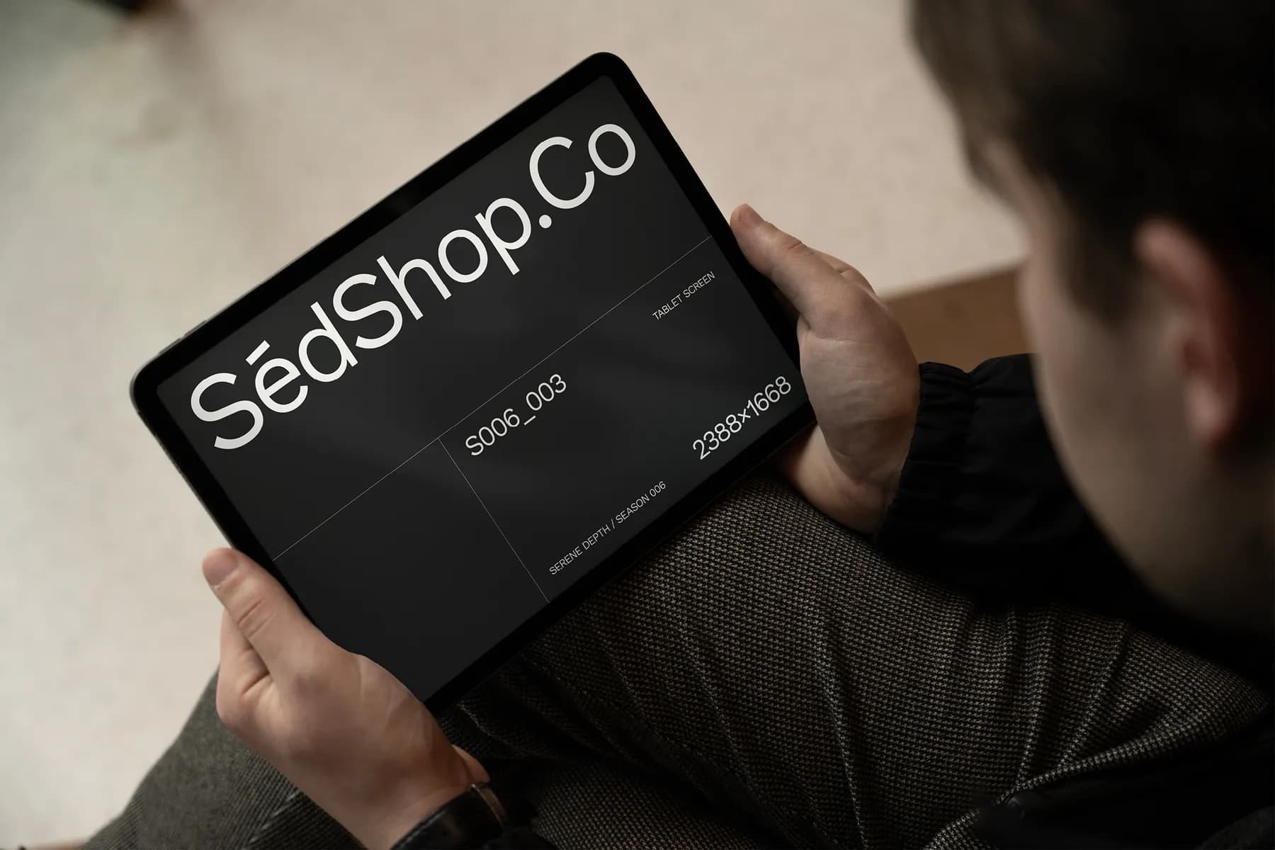 Close-up of a tablet screen mockup with dark screen, held by a person, showcasing detailed branding layout.