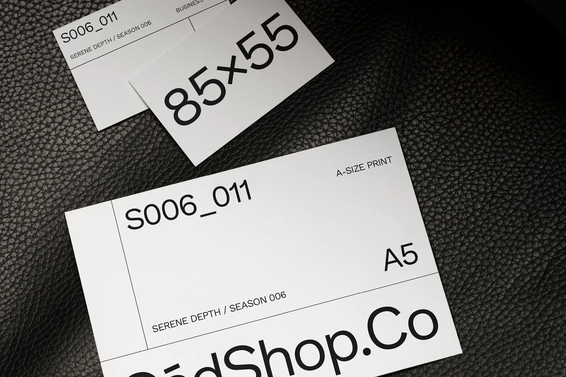 Close-up view of business cards and an A5 print card mockup, highlighting text and dimensions on a dark surface.
