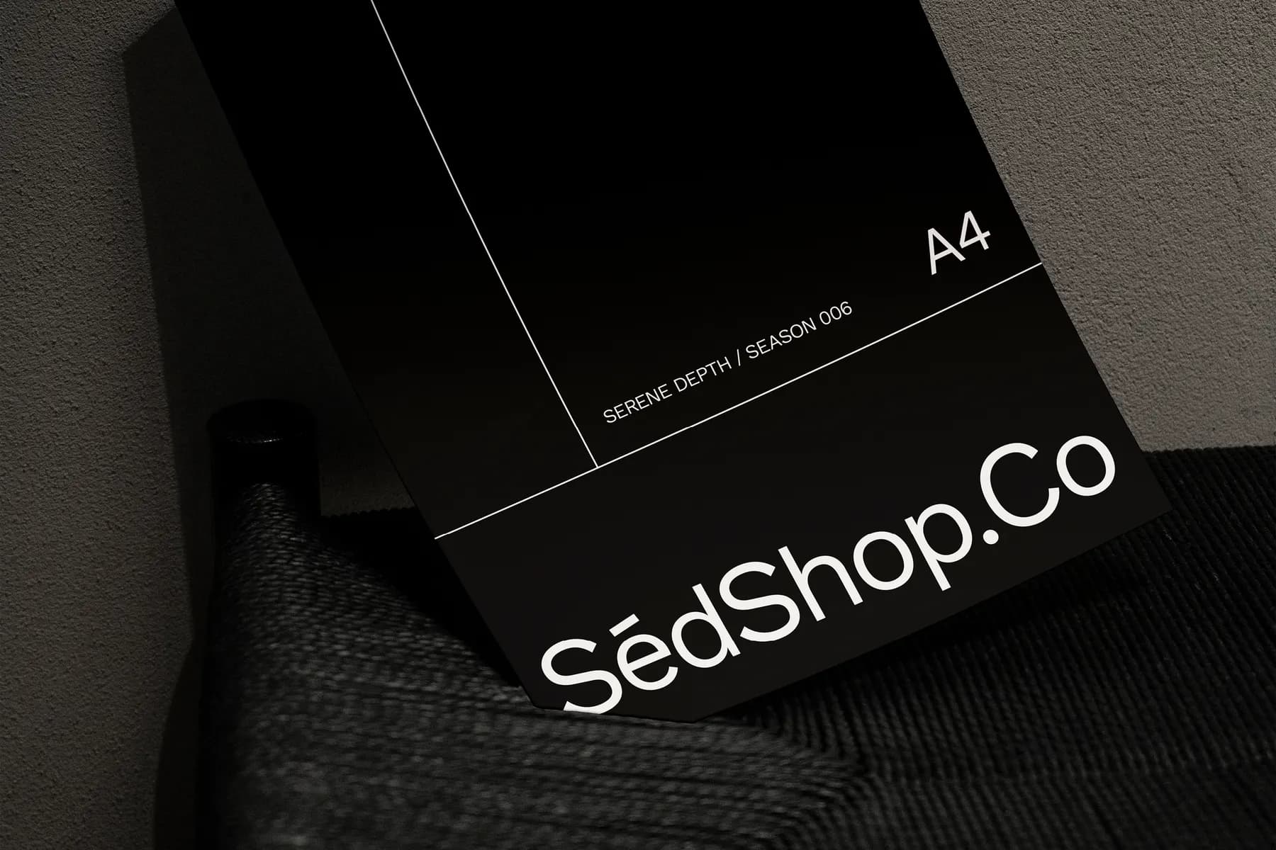 Close-up mockup of an A4 poster leaning on a chair, displaying SédShop.Co branding with a dark, minimalist design.