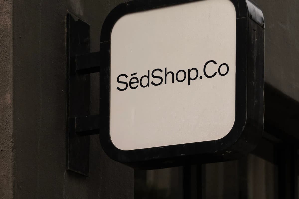Close-up view of a sign mockup attached to a building, displaying 'SédShop.Co' text, ideal for showcasing branding in an urban environment.